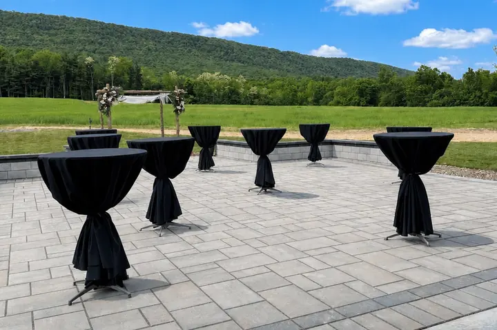 Cocktail tables in black linens on the stone patio, looking out toward Blue Mountain