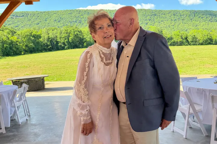 A couple sharing a kiss in the pavilion, with Blue Mountain behind them