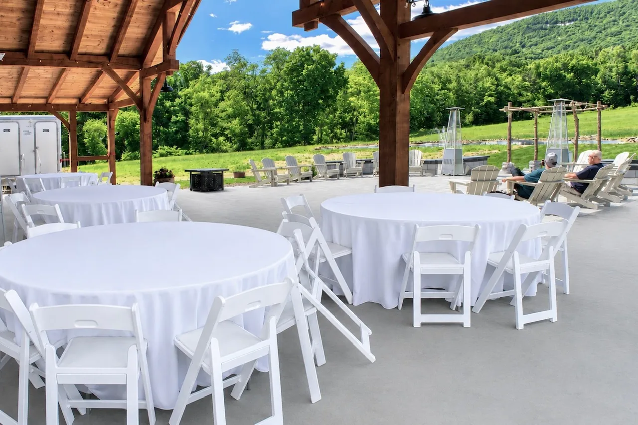Round reception tables in white linens under the pavilion, with Blue Mountain beyond
